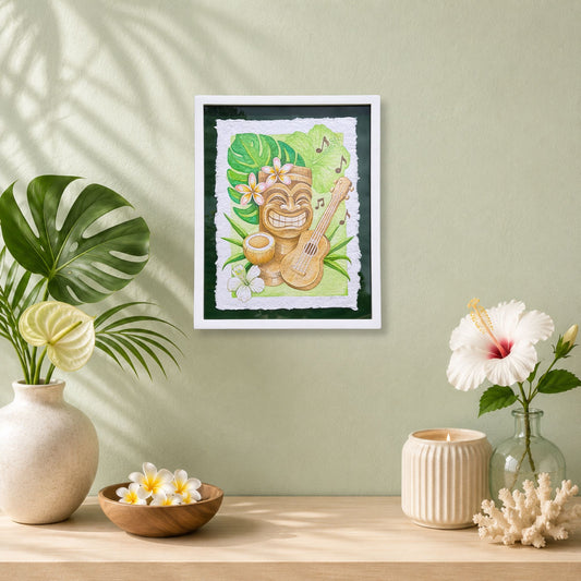 Luxury Hawaiian home with artwork of a tiki with a ukulele on a wall with decorative plants and vases. Framed artwork of a tiki, ukulele, and tropical flowers with leaves on a green background. Aloha Mele, watercolor painting on handmade paper, by Liliane Avalos, Kauai Hawaii 2026.