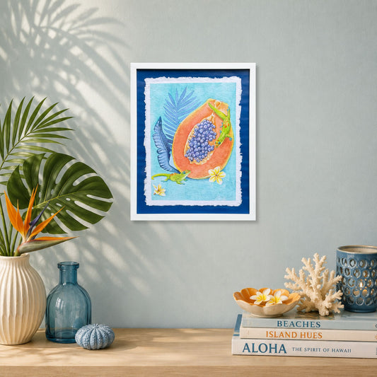 Luxury Hawaiian home with artwork of a Sunrise papaya with leaves on a wall above a table with decorative items. Framed artwork of tropical plumeria flower with palm leaves on a blue background. Good Morning Geckos, watercolor painting on handmade paper, by Liliane Avalos, Kauai Hawaii 2026.