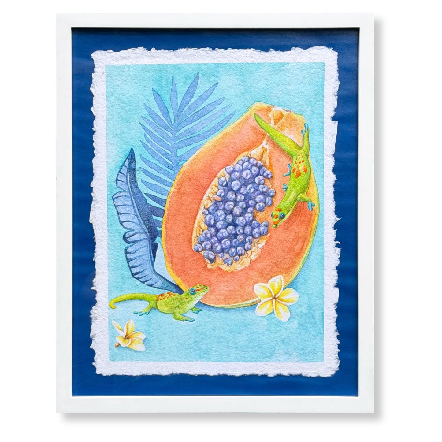 Framed artwork of a papaya with blue fruit and lizards on a blue background. Luxury Hawaiian home artwork of a Sunrise papaya with leaves on a wall above a table with decorative items. Framed artwork of tropical plumeria flower with palm leaves on a blue background. Good Morning Geckos, watercolor painting on handmade paper, by Liliane Avalos, Kauai Hawaii 2026. 