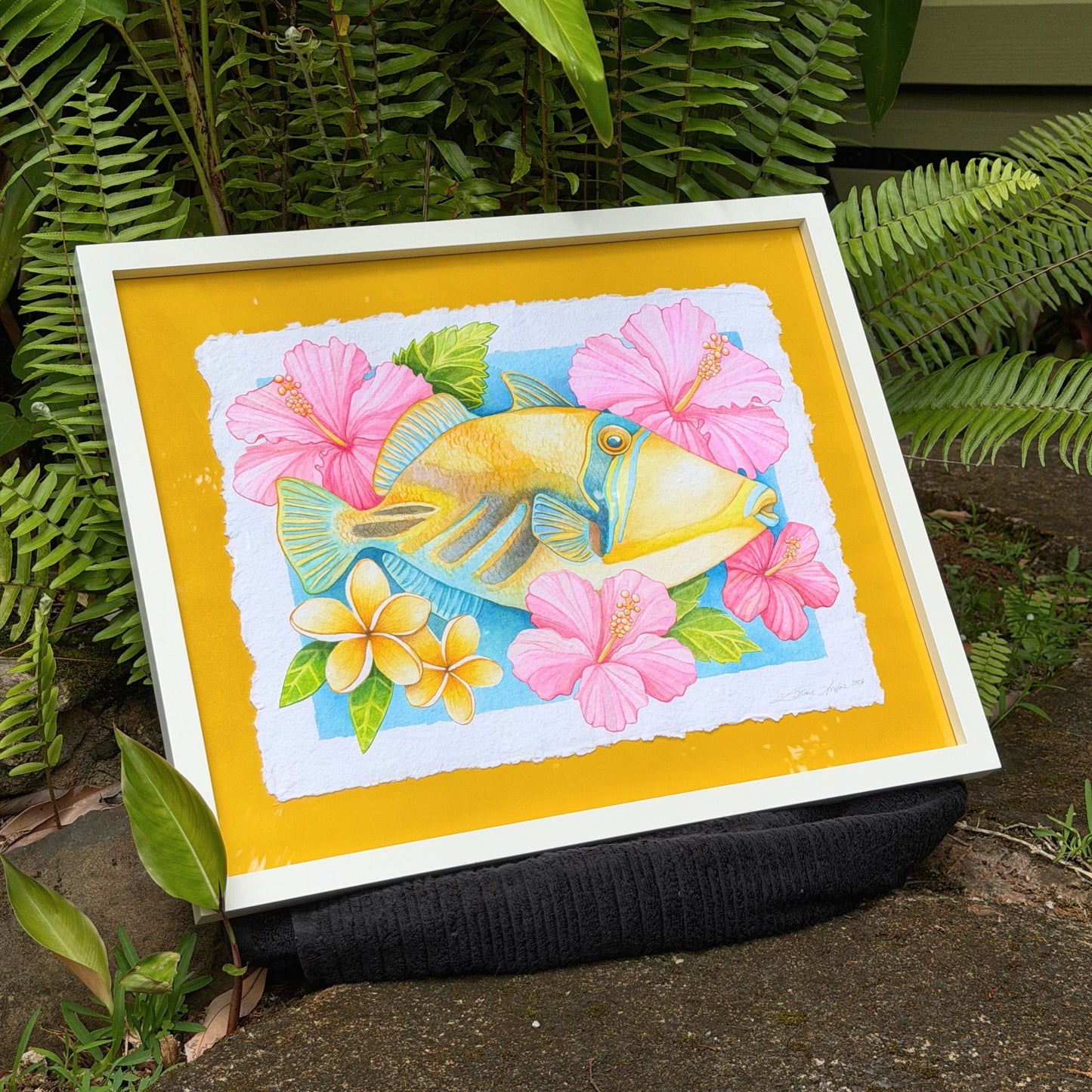 Framed watercolor painting of Humuhumunukunukuapua'a artwork color ful yellow trigger fish and hibiscus botanical flowers on a yellow background, white frame Humu_Harmony_2026_Liliane_Avalos_watercolor_painting_framed_Kauai_Hawaii_lifestyle