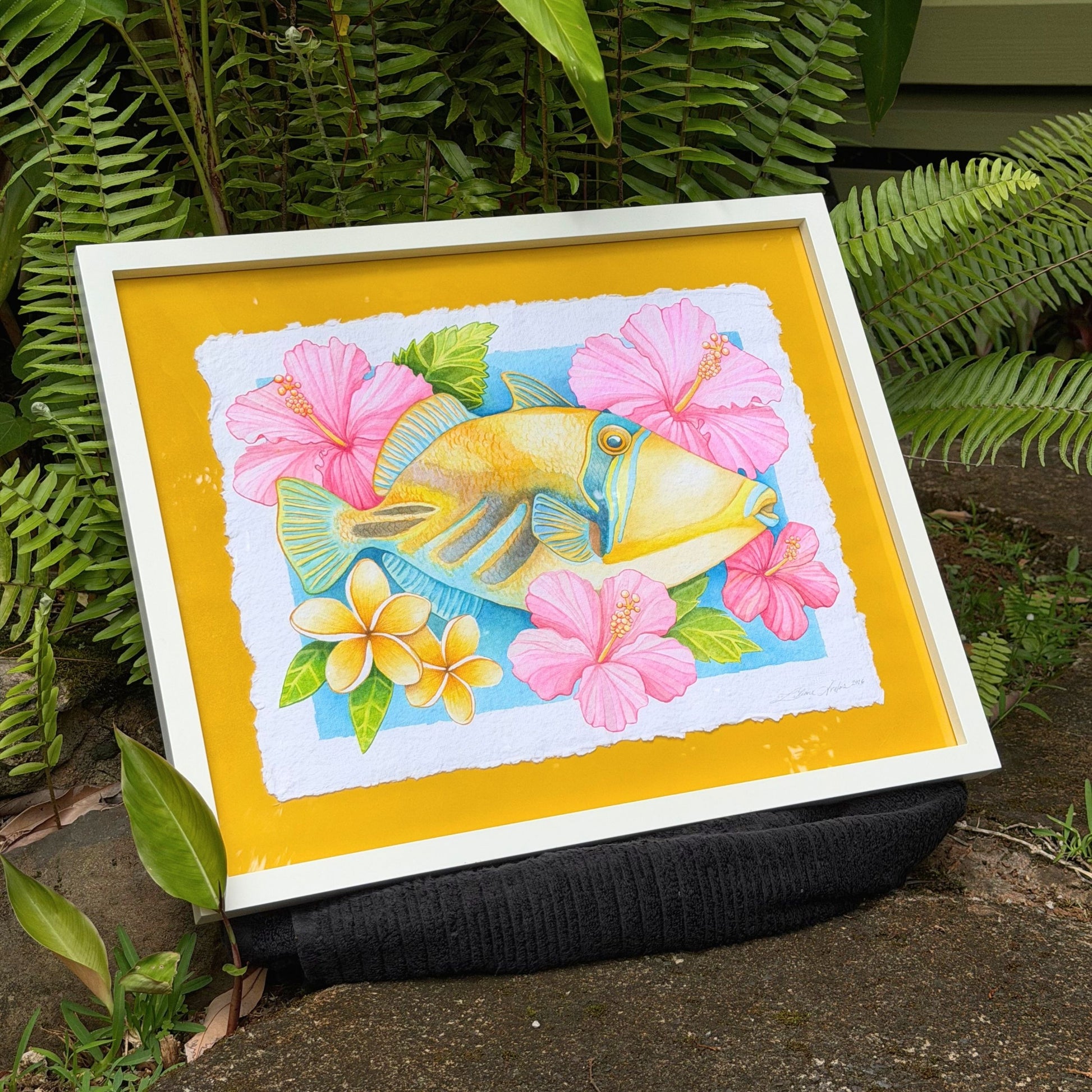 Framed watercolor painting of Humuhumunukunukuapua'a artwork color ful yellow trigger fish and hibiscus botanical flowers on a yellow background, white frame Humu_Harmony_2026_Liliane_Avalos_watercolor_painting_framed_Kauai_Hawaii_lifestyle