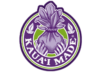 A circular purple and green logo featuring a lotus flower above a tied bundle of leaves, with the words 'KAUAI MADE' around the bottom edge, on a white background. featuring artist Liliane Avalos