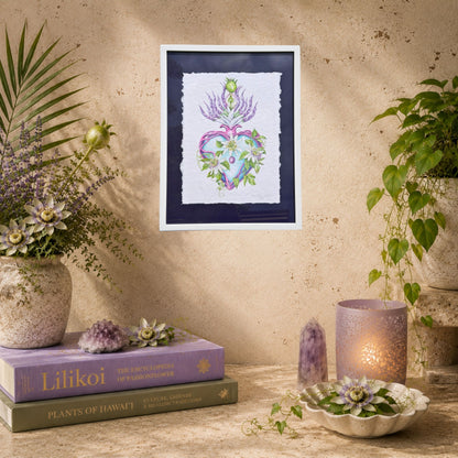 Framed artwork of a heart with flowers on a wall above books and decorative items. Framed original watercolor painting artwork with botanical sacred heart design featuring Lilikoi passion flowers and leaves on a white background of handmade paper, signed and embossed by artist Liliane Avalos