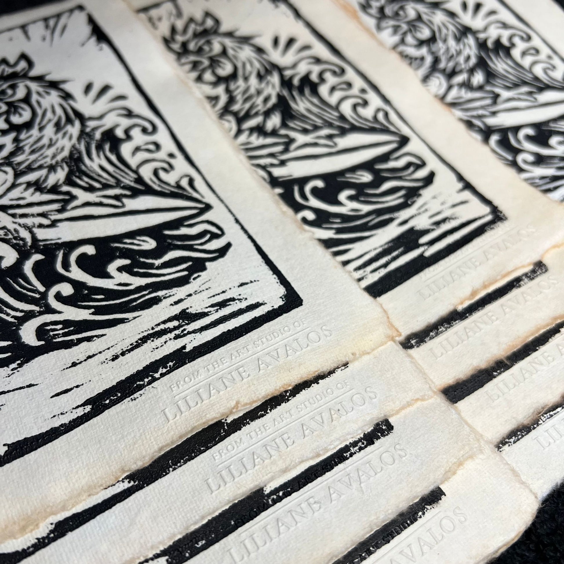 Linocut art prints with Surfing Rooster design in black ink on deckled edge paper. Surfing Rooster design with 'Liliane Avalos' branding custom emboss signature for authenticity