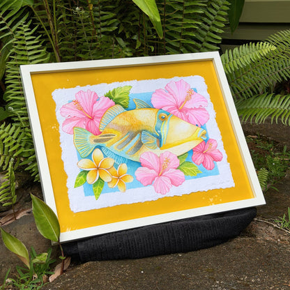 Framed watercolor painting of Humuhumunukunukuapua'a artwork color ful yellow trigger fish and hibiscus botanical flowers on a yellow background, white frame Humu_Harmony_2026_Liliane_Avalos_watercolor_painting_framed_Kauai_Hawaii_lifestyle
